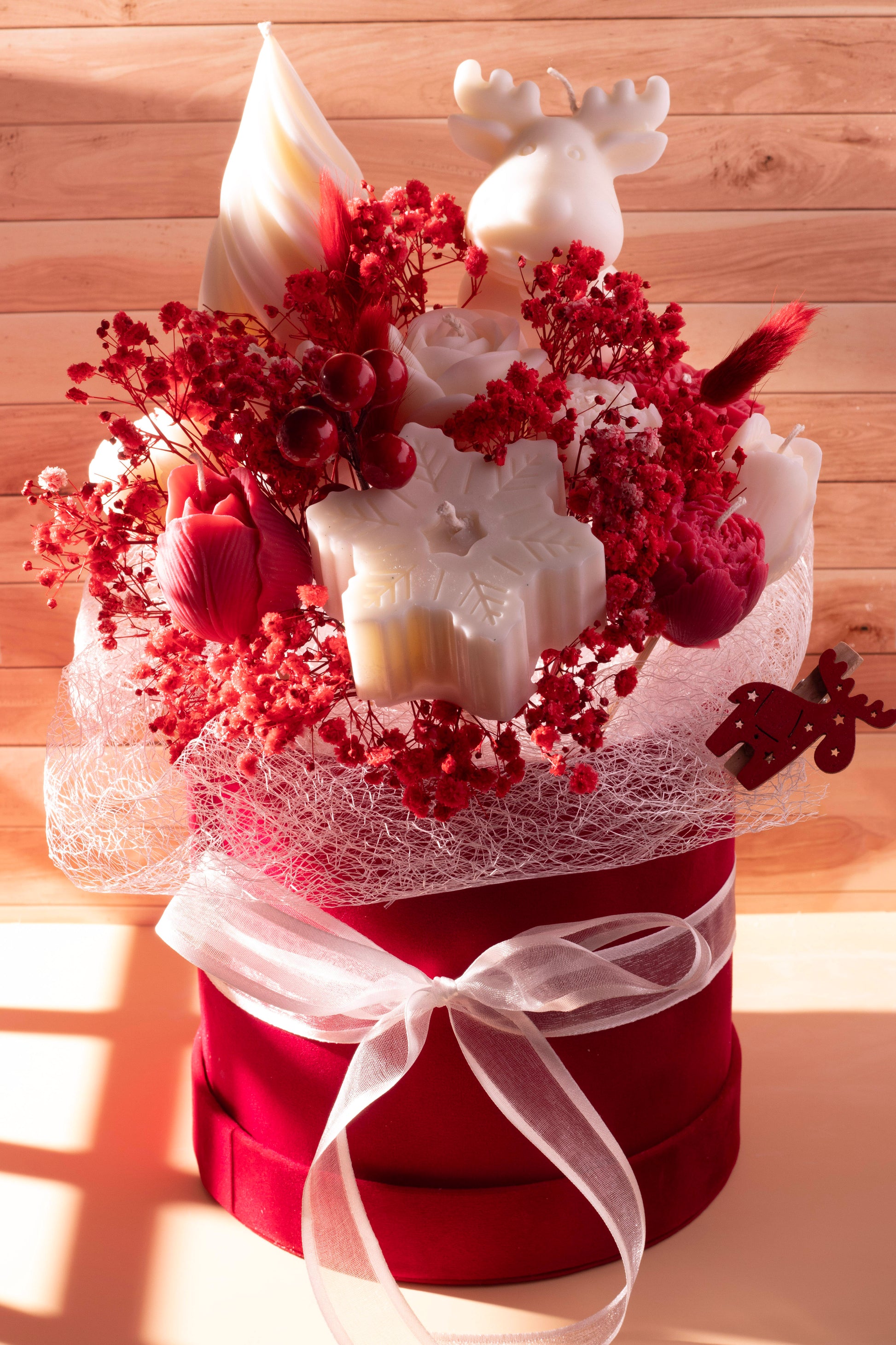Handmade Christmas wax bouquet with a white reindeer candle, red dried florals, snowflake wax pieces, and a red gift box with ribbon. Hand-poured in Cyprus.