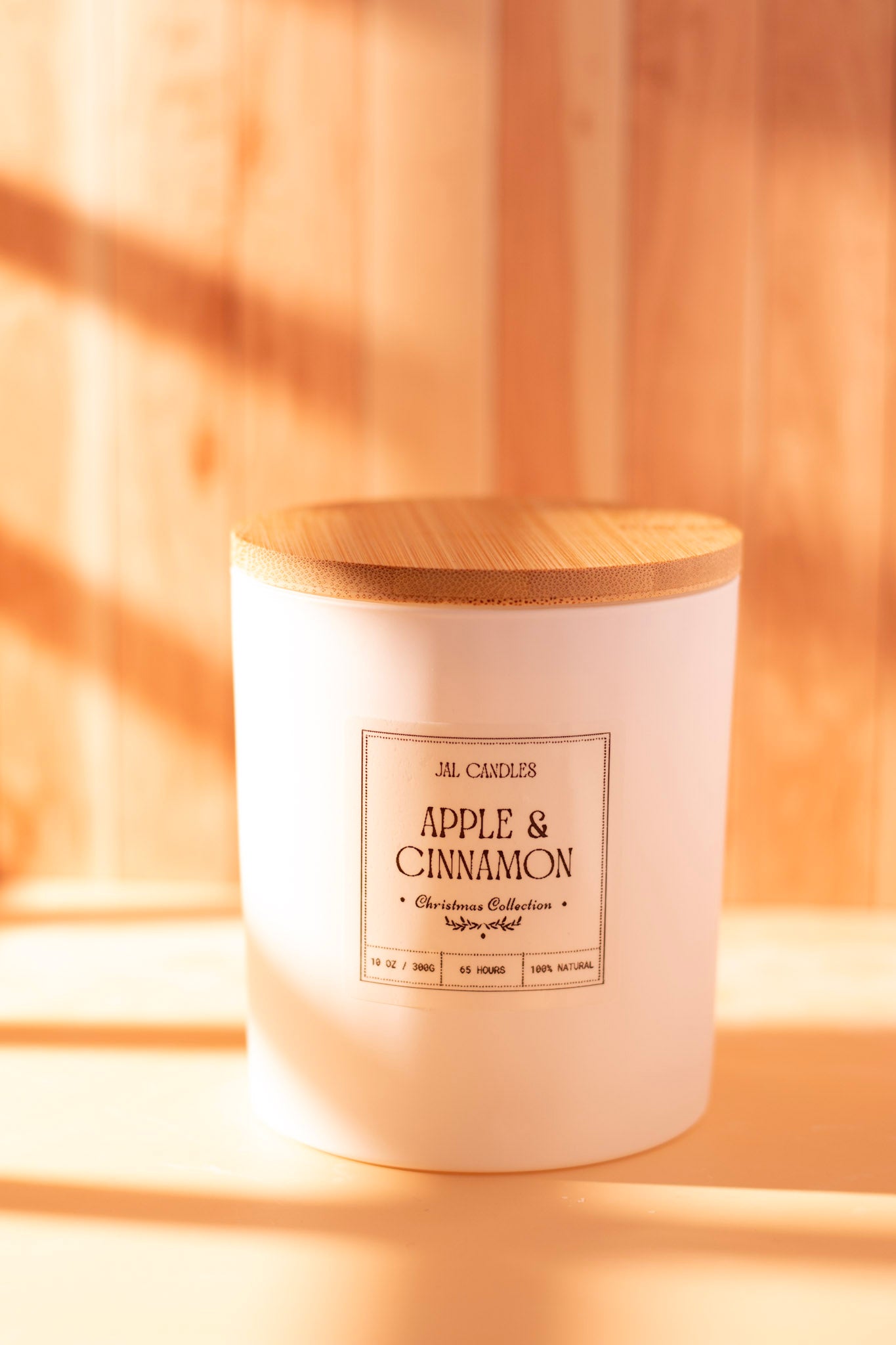 Apple & Cinnamon handmade candle in white cylindrical jar with wooden lid on warm background