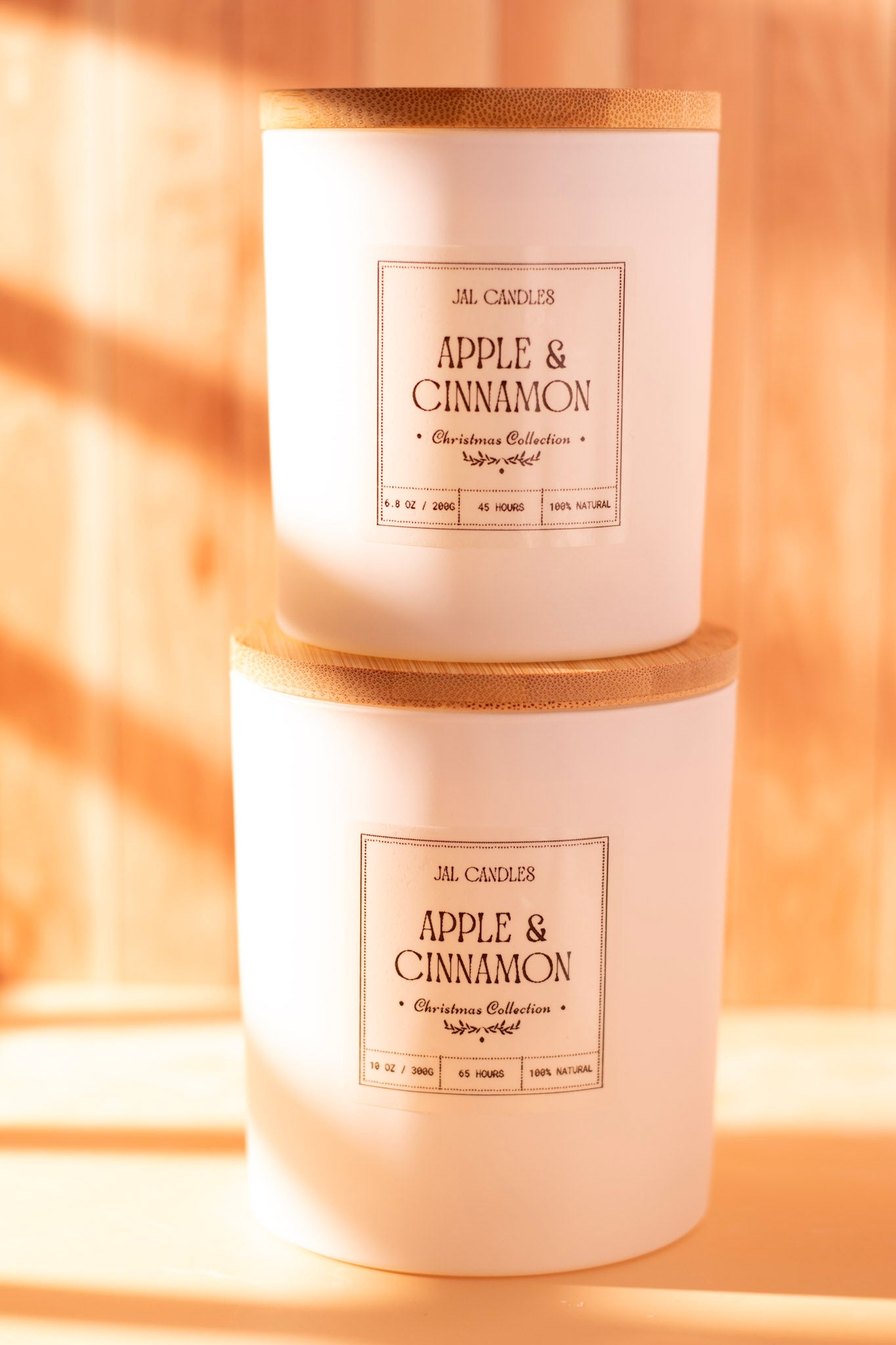 Two stacked Apple & Cinnamon handmade candles in white ceramic jars with wooden lids