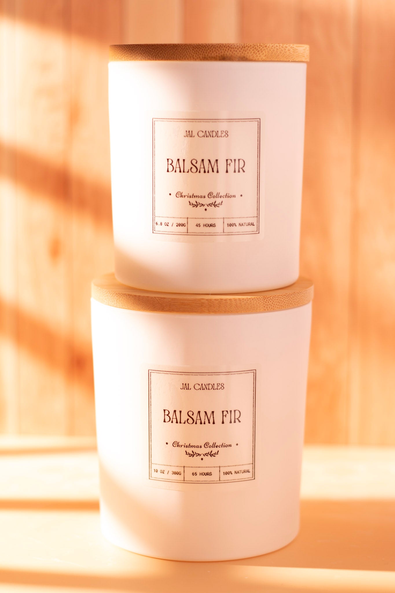 Two stacked Balsam Fir handmade candles in white ceramic jars with wooden lids