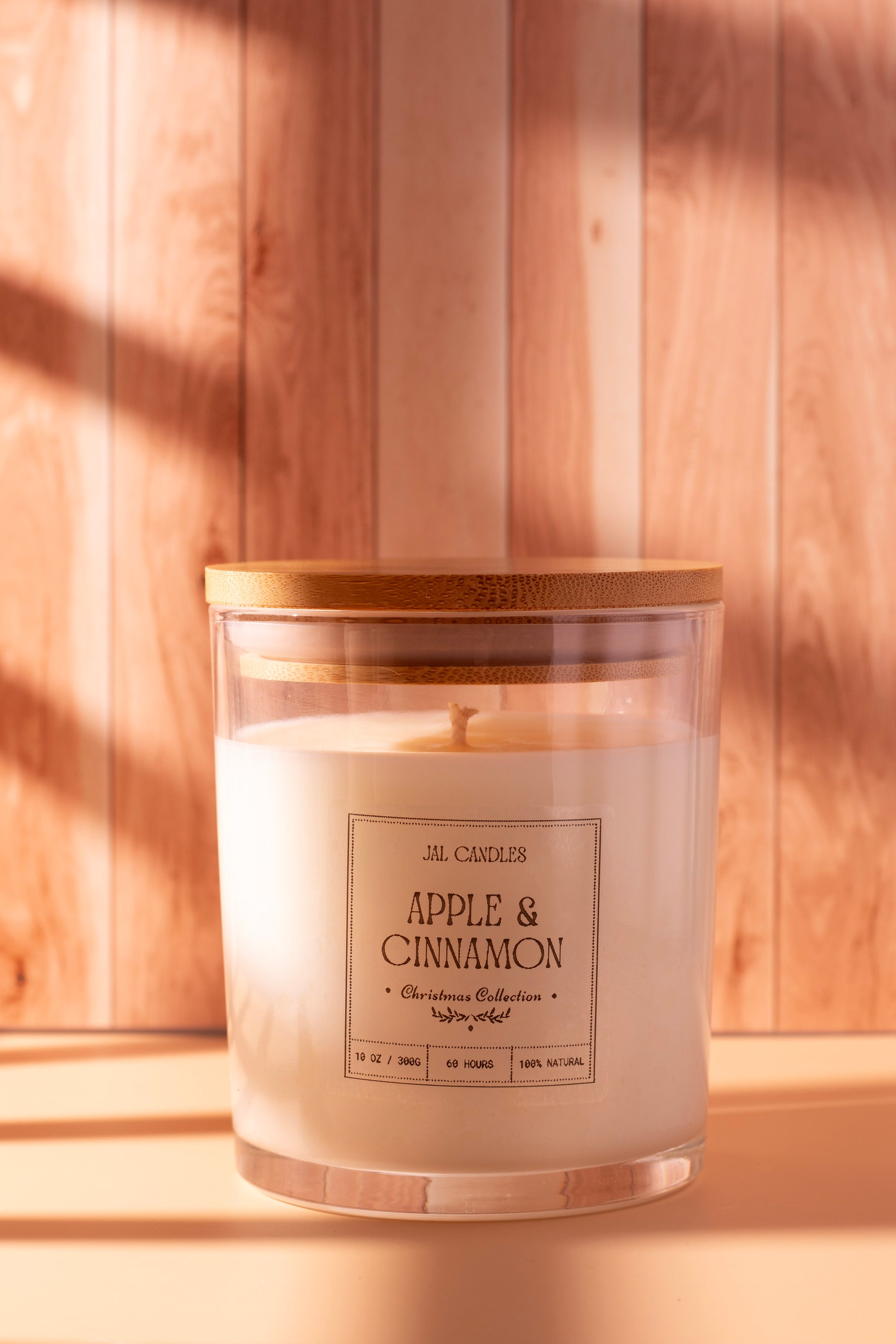 Hand-poured Apple & Cinnamon Christmas candle by JAL Candles, crafted from coconut-soy wax with a wooden lid, photographed in warm festive light, handmade in Cyprus.