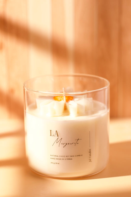 Clear jar candle with white daisy wax flower and orange centre on top