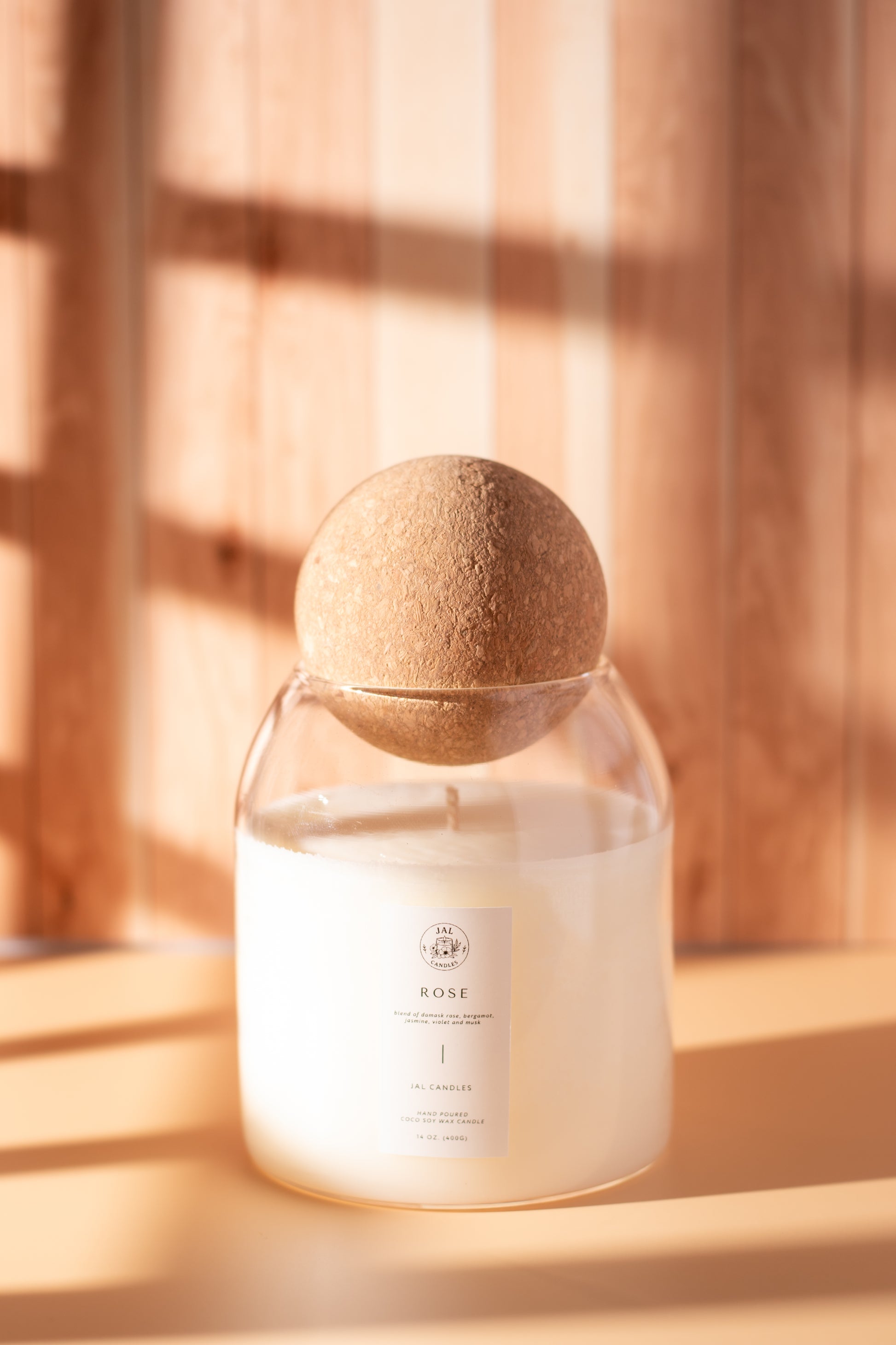 Hand-poured rose candle in glass jar with cork lid by JAL Candles, captured in warm sunlight on a wooden background, made in Cyprus
