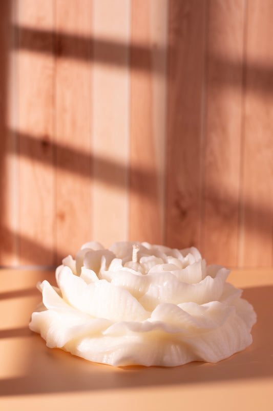 Handcrafted white peony flower candle by JAL Candles, sculpted from soy wax and photographed in warm sunlight on a wooden surface, made in Cyprus.